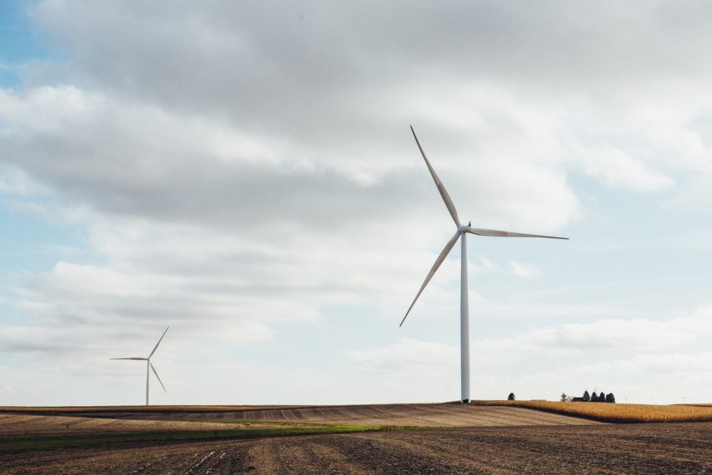 Two white windmills on brown field during the daytime