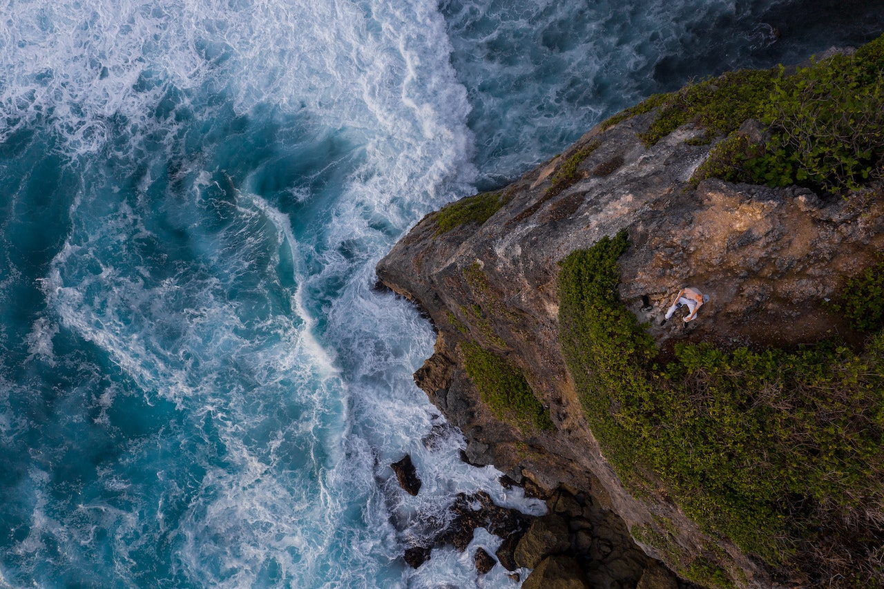 Man sitting on a cliff by the water