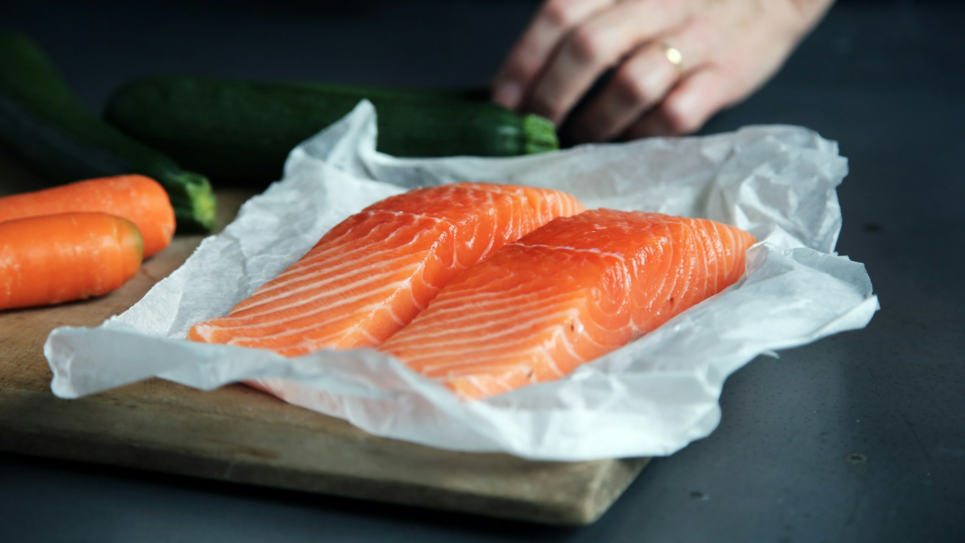 Raw salmon fillets on a paper-lined baking sheet