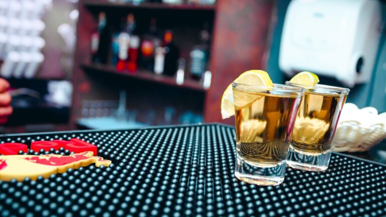 Close-up of tequila shots with lemon slices at a bar, ideal for nightlife scenes.