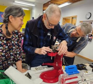 Woman watching volunteer repair coffee maker